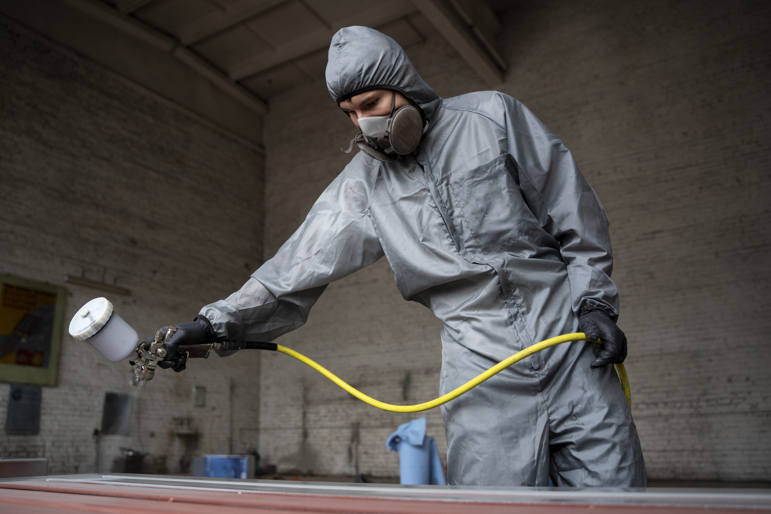 low angle worker spraying powder paint from gun