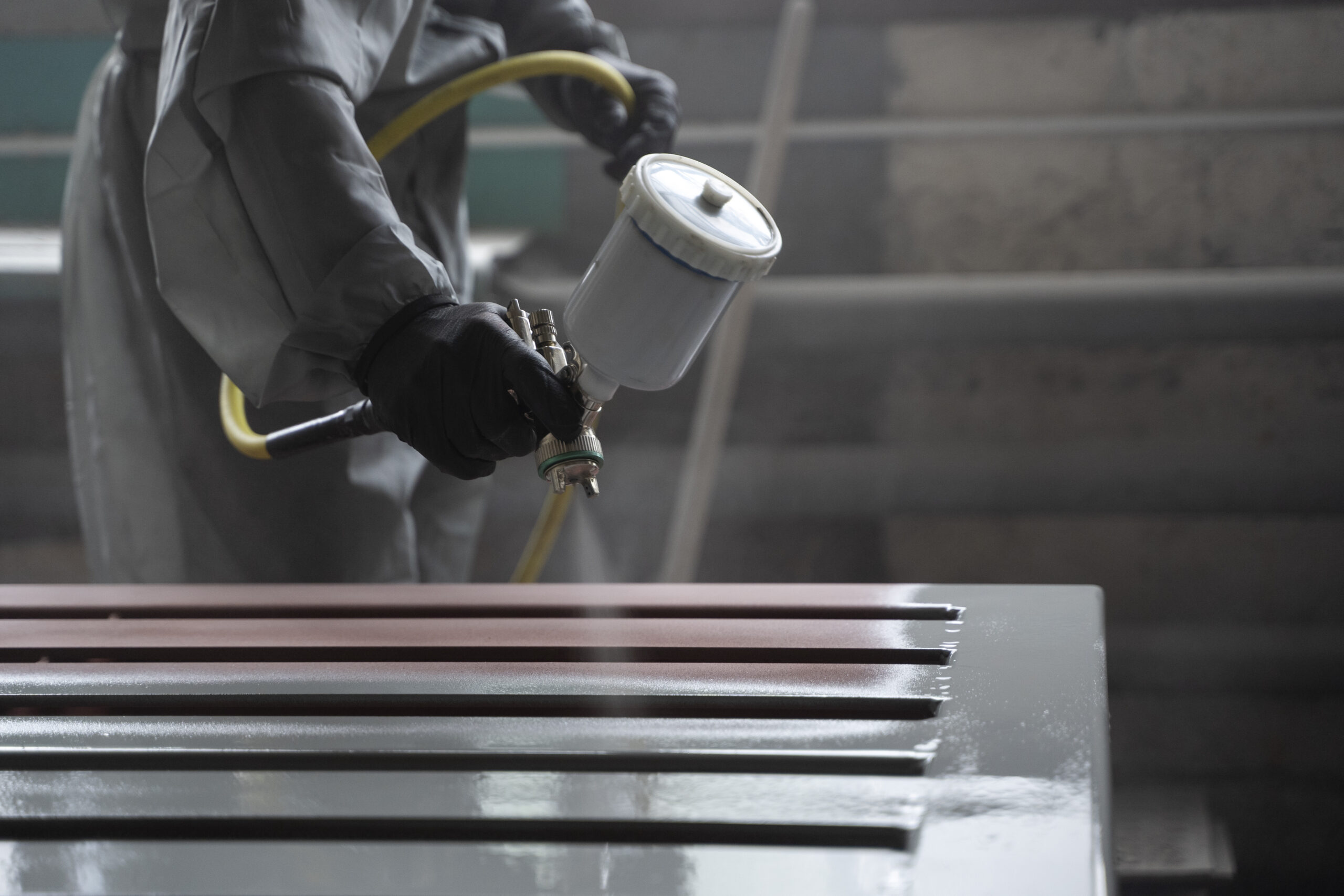 side view worker spraying powder paint from gun