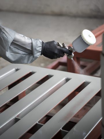 worker spraying powder paint from gun side view
